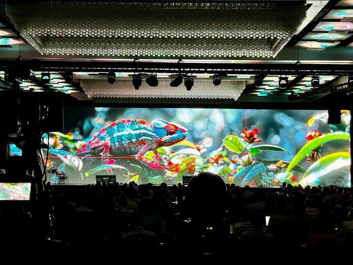Chameleon artwork on a full-width LED wall at a corporate event