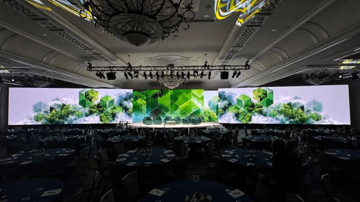 Green hexagon graphics on LED walls framing a panel discussion stage