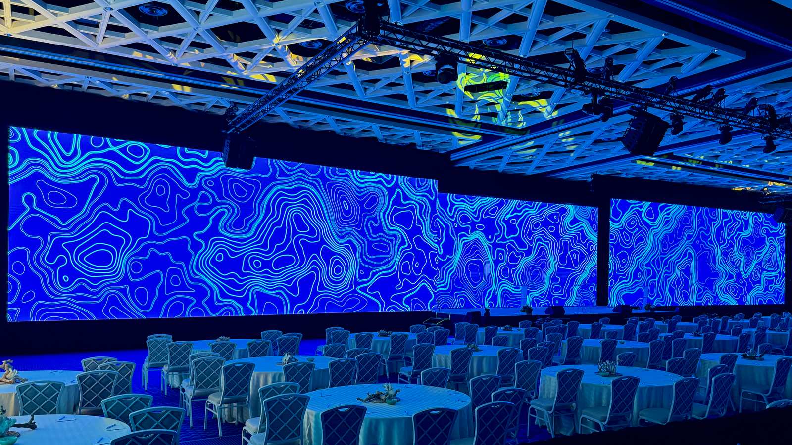 Blue topographic graphics across LED walls in a banquet room